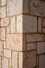 Composición de placas cuadradas de piedra rosada en esquina de muro