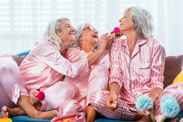 Beautiful senior women having funny pajama party at home - Group of cheerful elderly female friends doing make-up and having fun, concepts about old people, lifestyle and quality of life