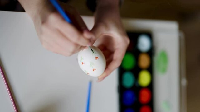 close up of woman hands coloring easter eggs with brush.