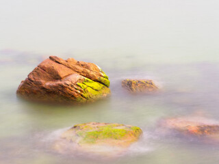 Rocks in the sea crashing against soft waves