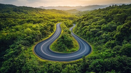 Fototapeta premium Serpentine Road Through Lush Green Forest in Mountainous Landscape