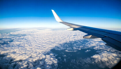 Obraz premium Stunning aerial view of fluffy cumulus clouds stretching to the horizon beneath a vibrant blue sky, seen from an airplane window. Perfect for travel, adventure, or freedom concepts.