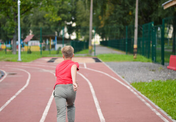 Attractive Caucasian boy runs around the stadium