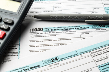 Filing the 2024 US 1040 individual income tax form with calculator and pen