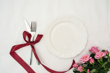 A Beautifully Elegant Table Setting Adorned with Lovely Roses and a Cursive red Ribbon
