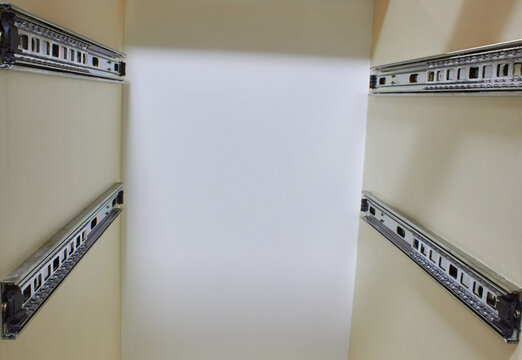 A metal drawer slide rail in furniture, white kitchen cabinet with metal slide guides for drawers, view inside the cabinet