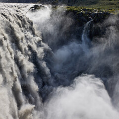 Dettifoss waterfall in Iceland.  Powerful cascade of water plunging into a canyon in Iceland. Mist and spray rising from the falls. Natural power and scenic beauty.