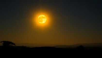 Fototapeta premium Golden Moon Rising Over Silhouetted Landscape