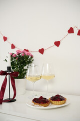 Valentines day table setting red roses and wine glasses, candle, plates with fruit cakes on white background. Valentine 's greeting card - Image