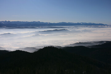 Scenic view of Tatra mountains and  from the top of Lubań mountain in Gorce, Poland. Area before mountains covered in thick mist.