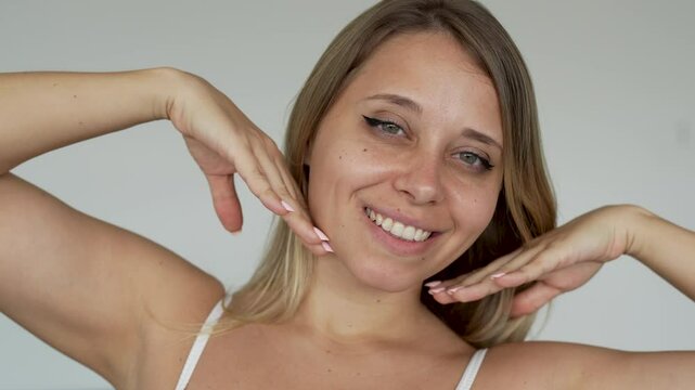 Young caucasian blonde woman with dimples on cheeks showing her beautiful smile a light grey background