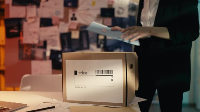 Detective puts cold case files into an archive box, continuing the investigation