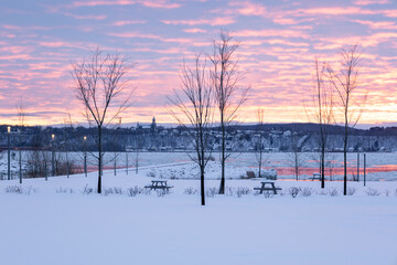 Pretty pastel winter sunrise over the St. Lawrence river seen from the linear park with jetty and benches on Champlain Boulevard, Quebec City, Quebec, Canada