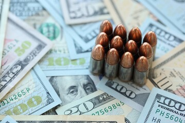 Pistol bullets and cartridges lies on many dollar bills