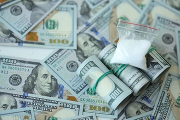Fototapeta premium Small cocaine dose in plastic ziplock packet lies on big amount of american currency banknotes