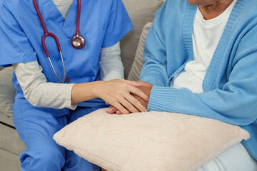 Nurse gently holding hands of elderly woman during home care session. Focus on emotional support, trust-building, and compassionate interaction for patient rehabilitation.
