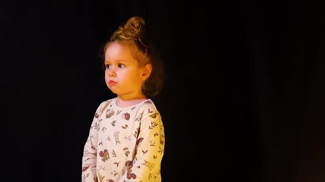 Little girl on a black background is offended