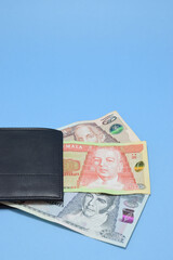 Quetzales y una billetera sobre un fondo celeste, dinero de Guatemala. Espacio para texto en la parte superior.