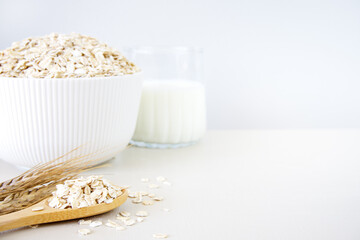 Oat flakes in bowl and milk on white table