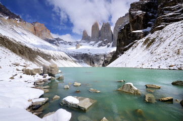 Beautiful view of the three snow-capped towers of the Torres del Paine National Park with the opaque blue glacial lake in the foreground