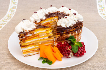 Delicious layered cake with fruit and cream topped with chocolate glaze