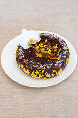 Chocolate cake with yellow decoration and white orchid on a plate