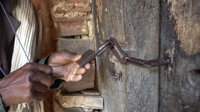 Orthodox Ethiopian priest uses keys to open wooden door of rock-hewn Abuna Yemata Guh monastery in mountains of Tigray, religion in remote location Africa
