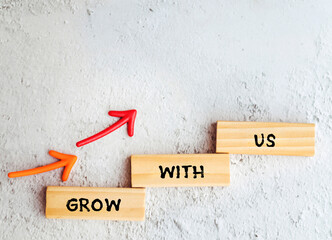 Wooden blocks with words Grow with us and arrows .Business concept 