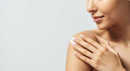 Close-up of a woman applying body cream on her shoulder, emphasizing skincare and body care routines