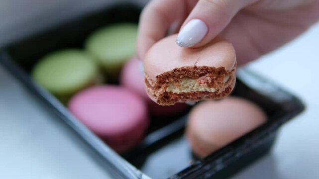 Hand holding macaron on nature background. A Macaron is a sweet meringue-based confection made with egg white, icing sugar, granulated sugar, almond meal, and food colouring.