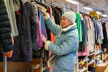 Woman browsing clothes in a thrift shop. Second hand concept	
