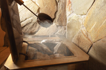 Close-up Hot stones in furnace for produce steam and heat in steam room. Steam an water on the stones, spa and wellness concept, relax in hot finnish sauna. Interior of wooden sauna