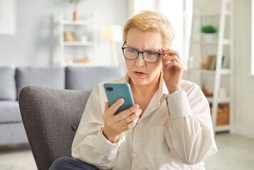 Senior shocked concerned cellphone female user staring at screen, elder woman at home looking at smartphone screen, problem with online app, poor Internet service, getting surprising bad news, mistake
