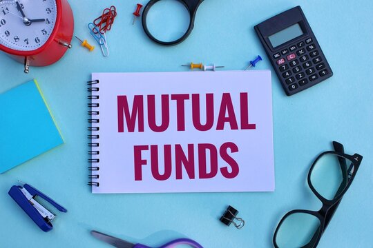 MUTUAL FUNDS - words on a white sheet against the background of banknotes, magnifying glass and calculator 