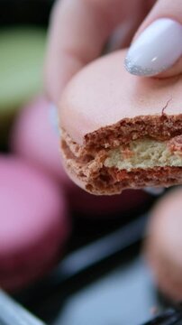 Hand holding macaron on nature background. A Macaron is a sweet meringue-based confection made with egg white, icing sugar, granulated sugar, almond meal, and food colouring.
