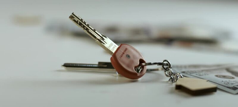 Low angle close-up view of a bunch of apartment keys with wooden keychain falling down. Shot in slow-motion