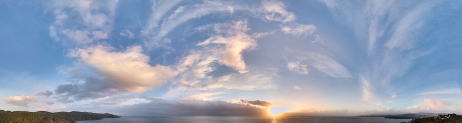 Obraz premium Panoramic Sunset Over Ocean and Hills With Dramatic Cloud Formations