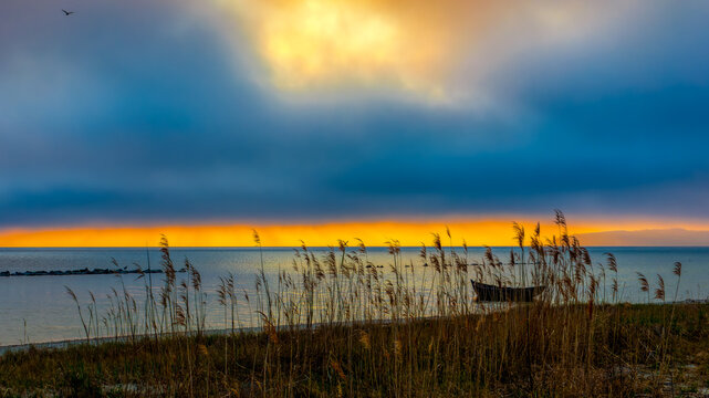 Fishing boat in the bay in front of reeds with dramatic sky and reef grass in front
