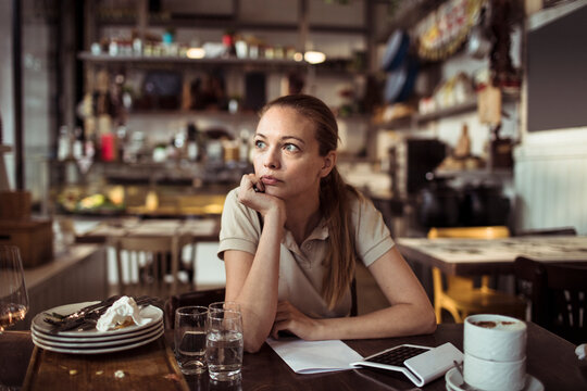 Waitress thinking while calculating bills in a cozy restaurant bistro