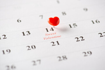 Close-up of a calendar, February 14th marked with a heart pin symbolizing Valentine's Day