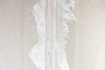 Preparing drywall for plaster. The seam on the plasterboard wall is filled with putty