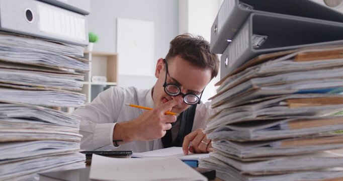 Freaky and funny businessman wearing eyeglasses working with documents in the office, humorously writing and handling accounting tasks. Work routine showcasing unusual yet productive business audit.