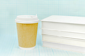 Coffee in paper cup and a stack of books on a light blue checkered background