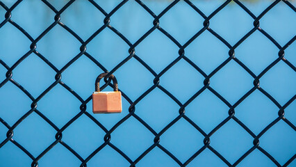 Closeup of a lovelock with a rusty shackle on a chain-link fence along an urban riverwalk in...