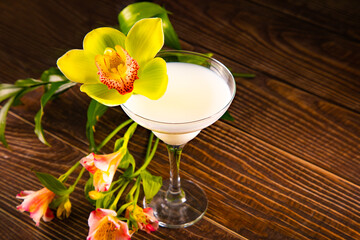 Cold green exotic cocktail with decorated flowers orchid and palm leaves. Tropical vibes.