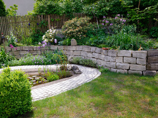 Gartenteich mit Steinmauer und vielen Pflanzen 