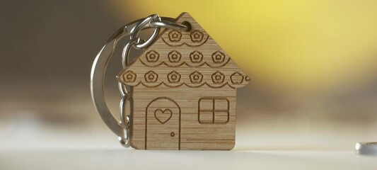 Extreme close-up view of a handmade wooden house shaped keychain on the table. Homeownership and real estate concept - Powered by Adobe