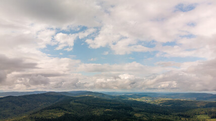 Majestic Mountains, Lush Green Forests, And Soft White Clouds On A Sunny Day. Aerial View Showcasing The Stunning Beauty Of Nature From A High Perspective.