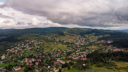 Obraz premium Stunning Aerial View Of A City Nestled Between Majestic Mountains And Lush Forests, With Clouds Gently Rolling Over The Landscape, Creating A Picturesque Scene.
