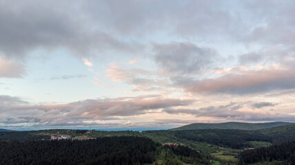 Majestic Mountains, Lush Green Forests, And Soft White Clouds On A Sunny Day. Aerial View Showcasing The Stunning Beauty Of Nature From A High Perspective.	
